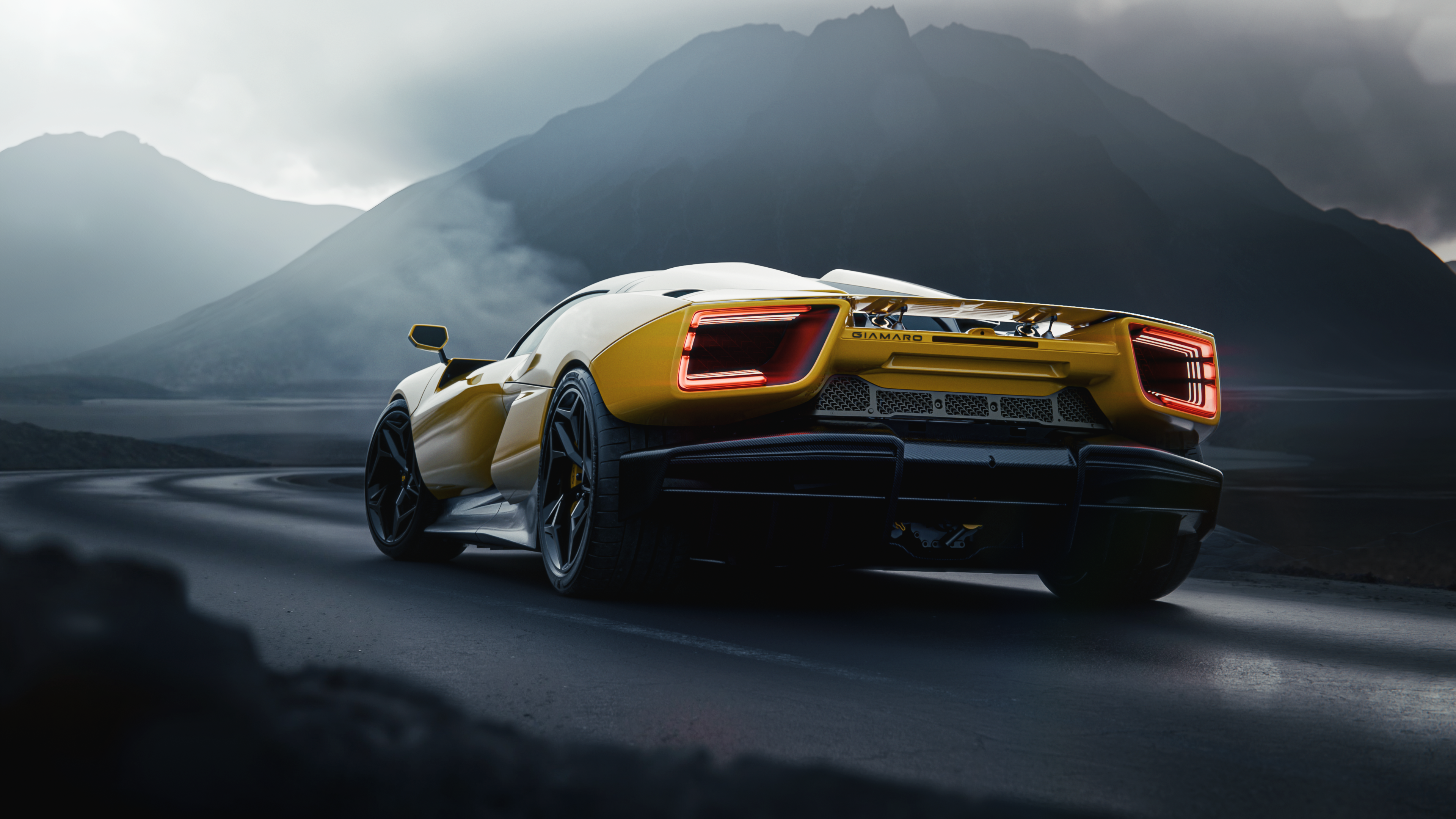 A rear view of the yellow Giamaro Katla on a winding road with mountains.