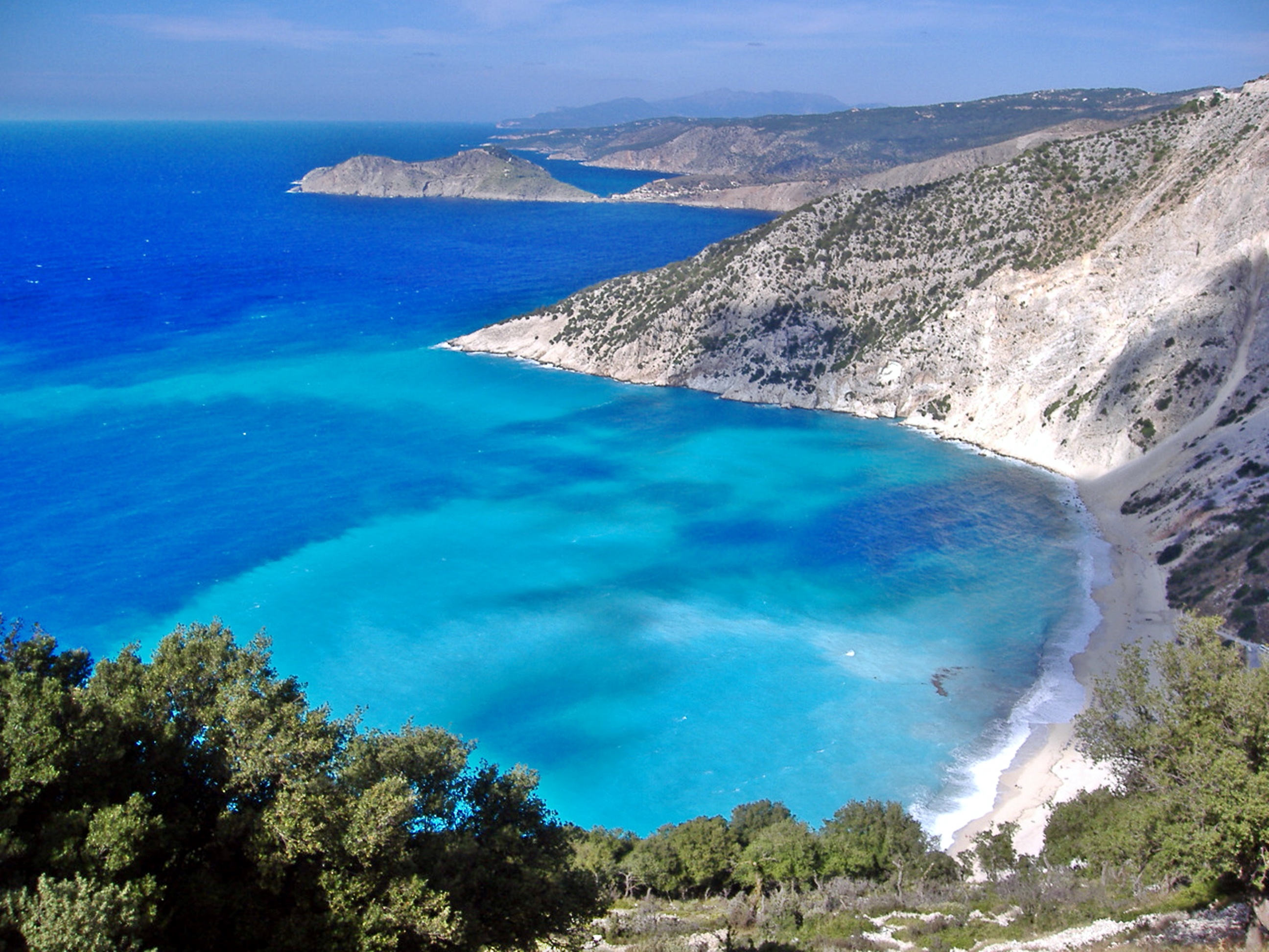 An image of the coast of Kefalonia, Greece, with turquoise water and green mountains.