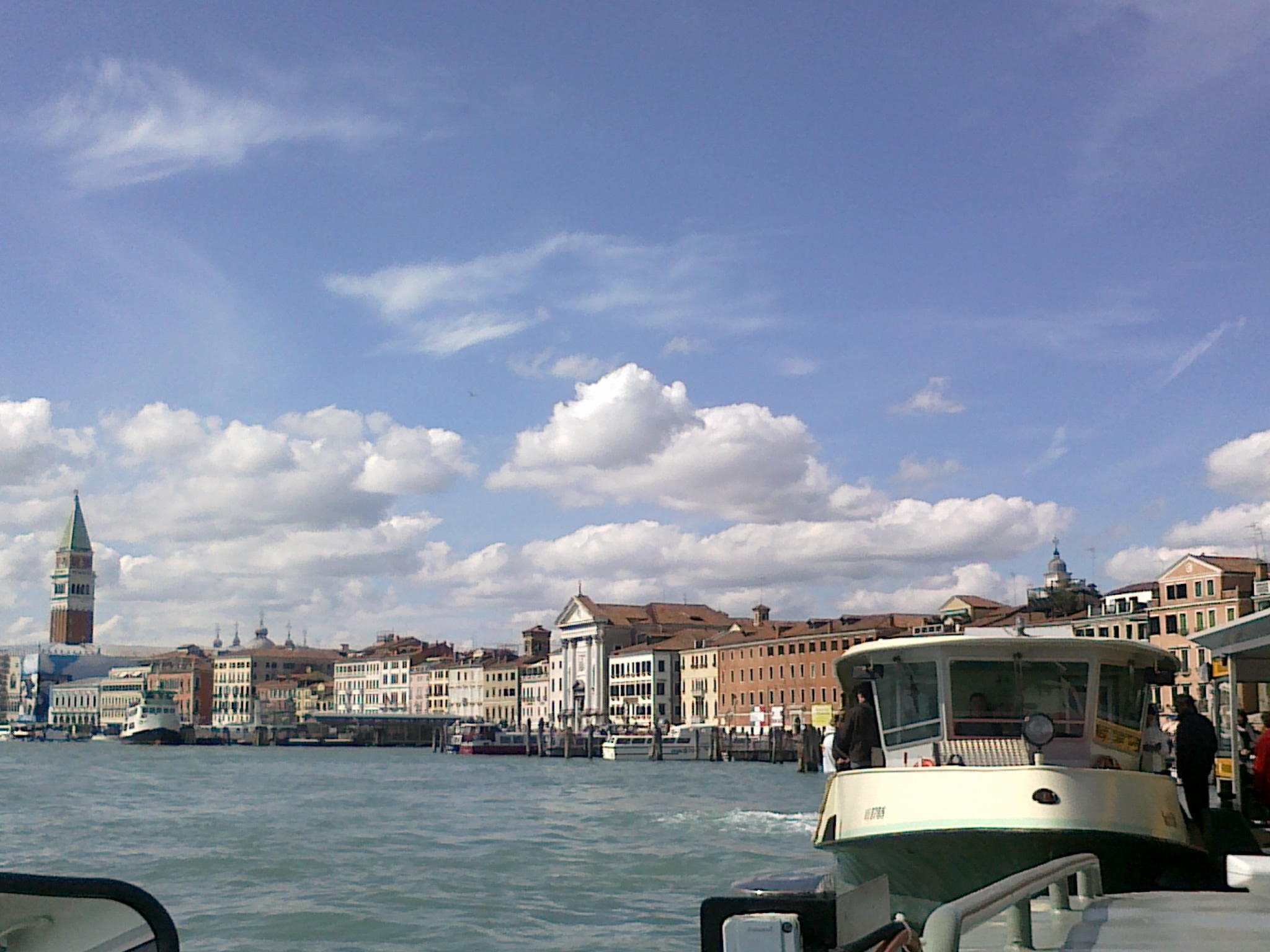 View from a boat on the Grand Canal showing waterfront buildings and a large ship.